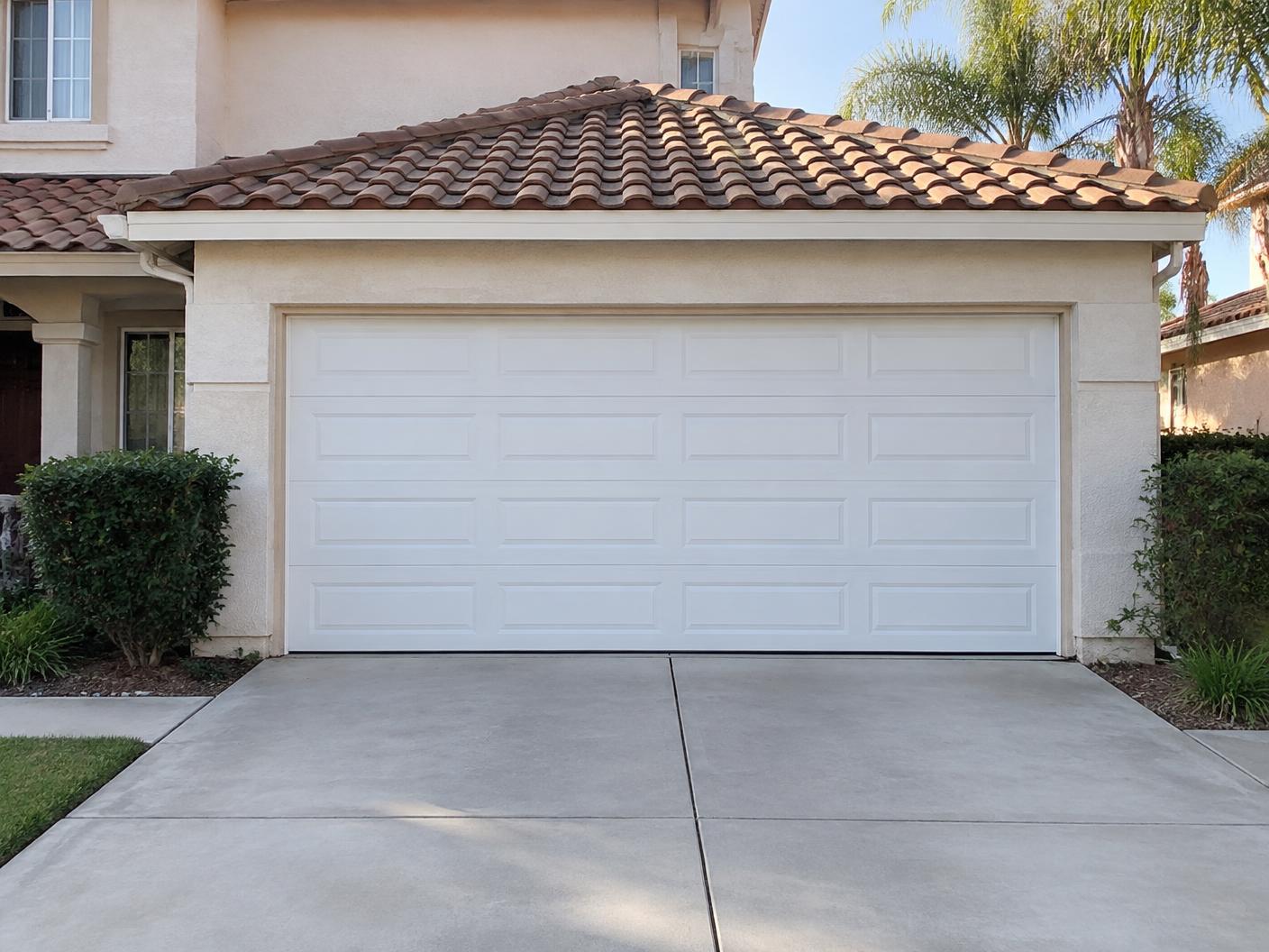 New white paneled garage door installed on the same stucco home